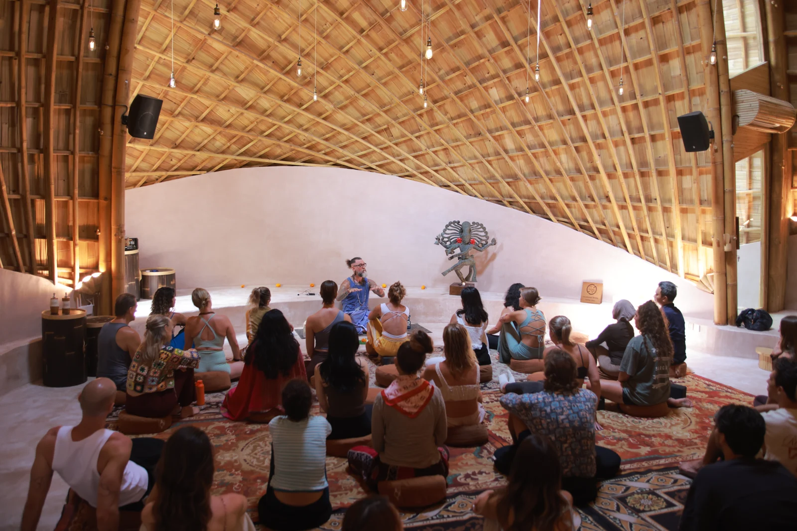Ashton teaching a seated group beneath a bamboo roof at Alchemy.